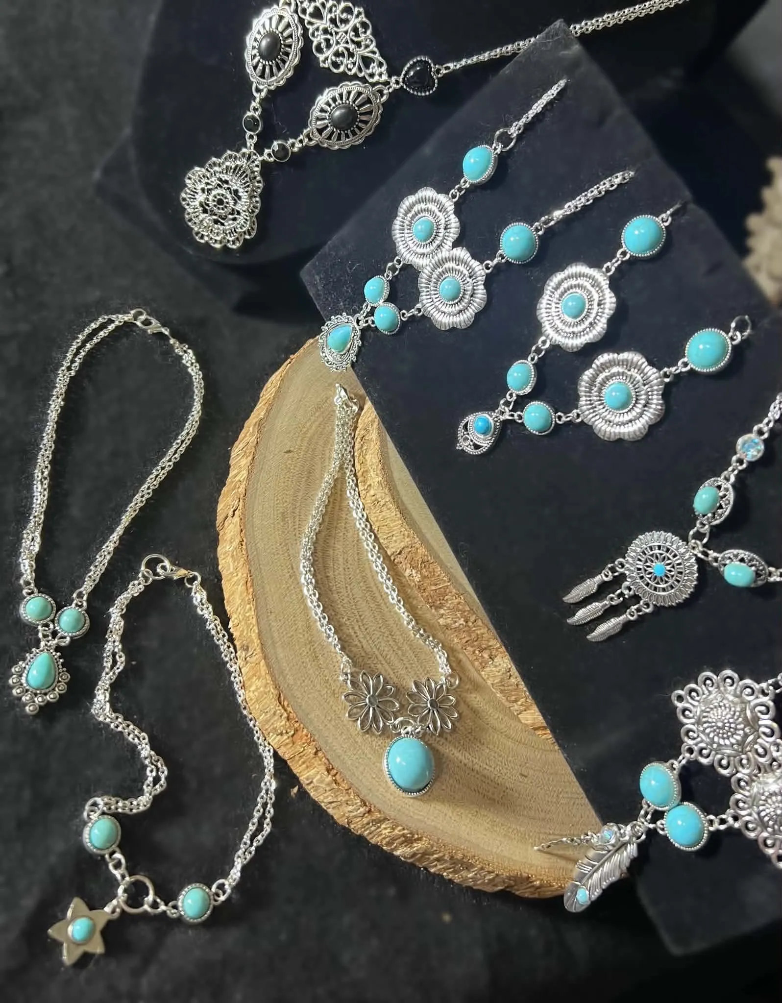 Assorted handcrafted western jewelry laid out on velvet and a wood slice